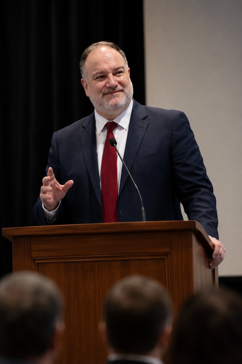 Christopher J. Ewing speaking at a lectern before an audience